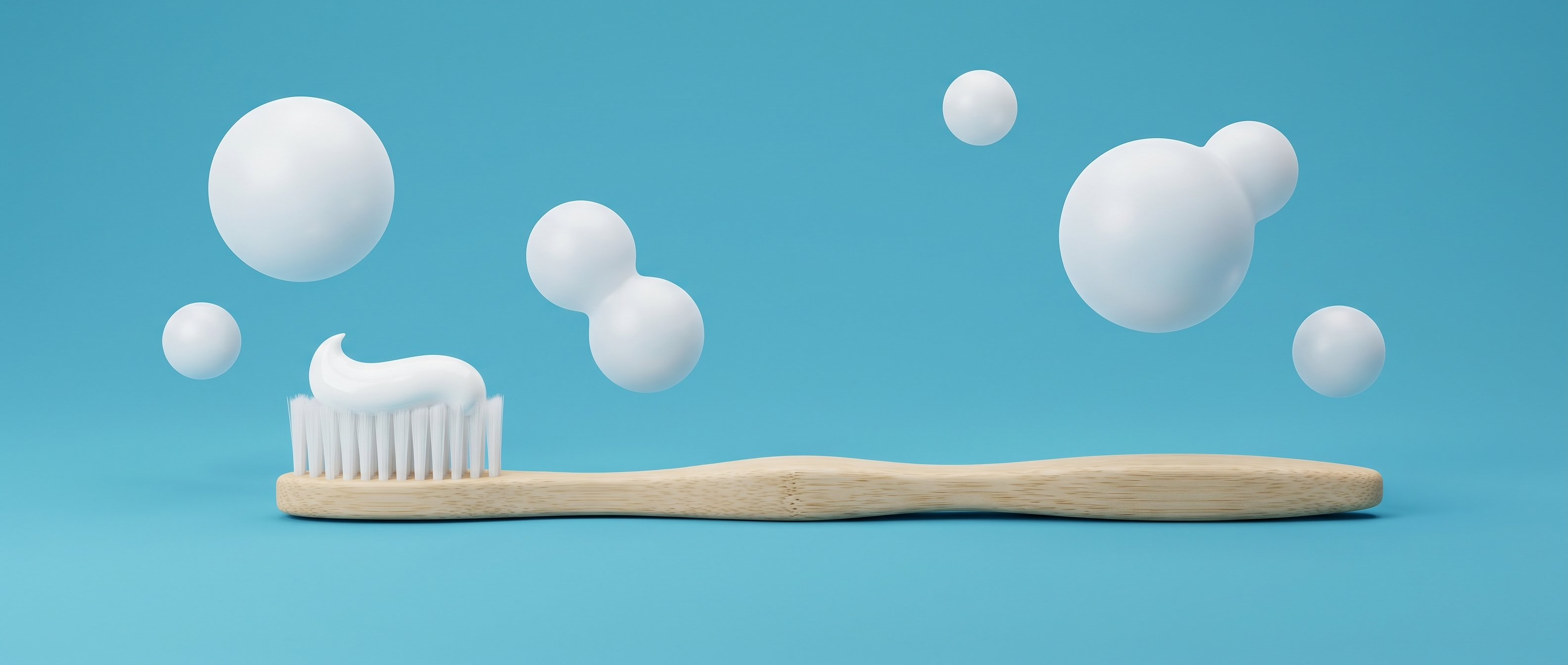 Bamboo toothbrush with a swirl of toothpaste and soft floating bubbles on a mid-blue background