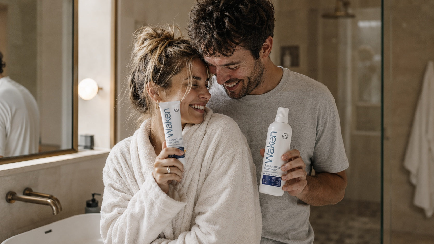 Couple in a hotel bathroom with Waken Advanced Care toothpaste and mouthwash
