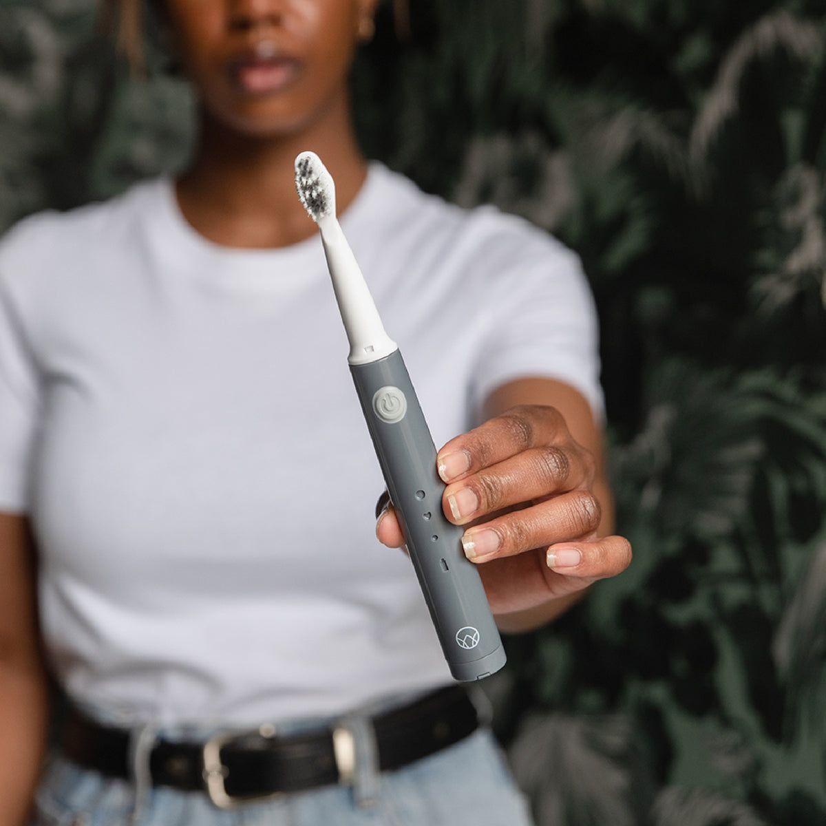 A woman holding the Waken Sonic Toothbrush in Graphite Grey